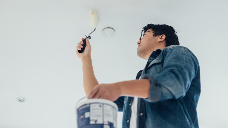 A man paints a ceiling white