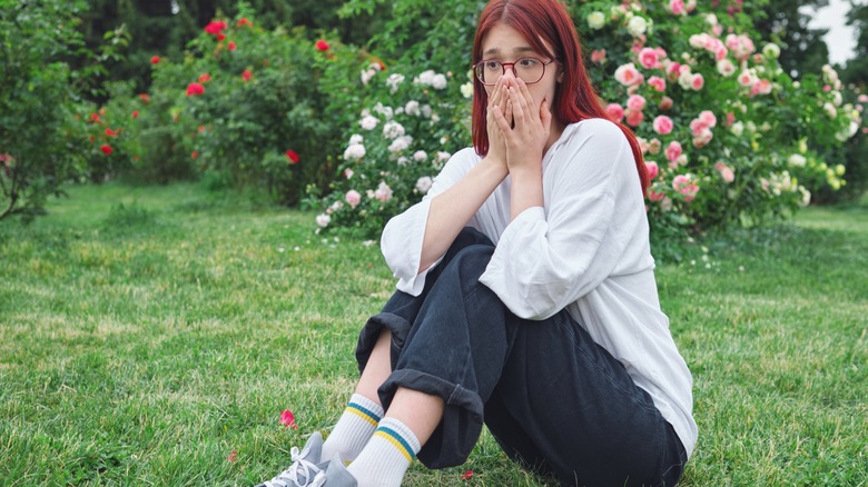 Woman covering nose in garden