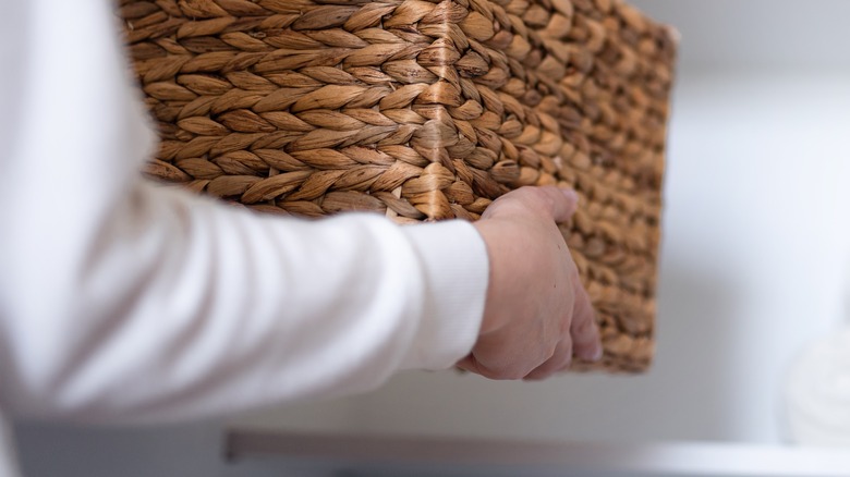 person picking up woven basket