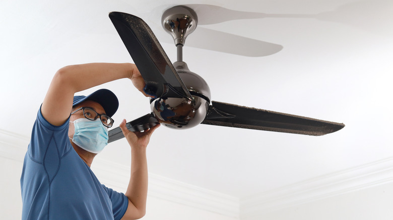 Person cleaning ceiling fan