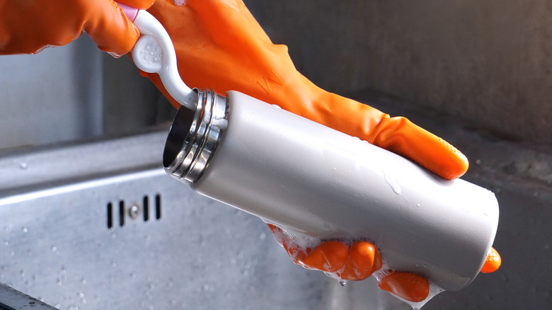 Hands cleaning metal water bottle