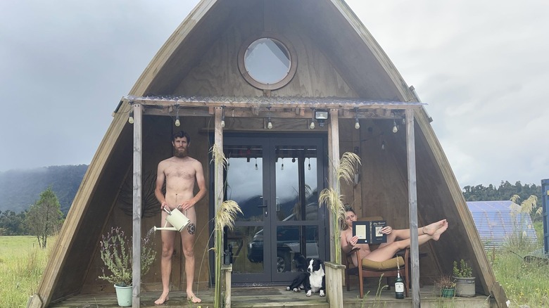 couple posing semi-naked in front of house