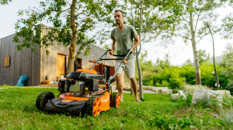 A man using his lawn mower on his lawn