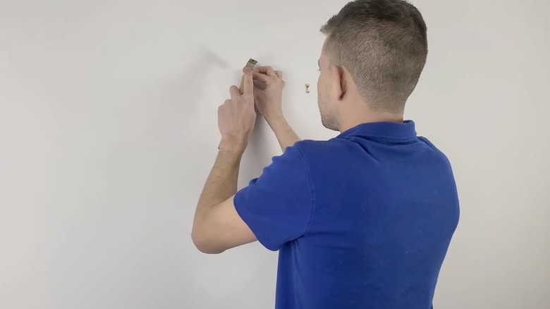 Man hammering picture hangers on wall