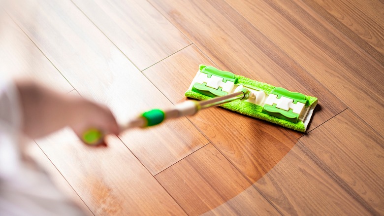 Homeowner dust mopping wooden floor