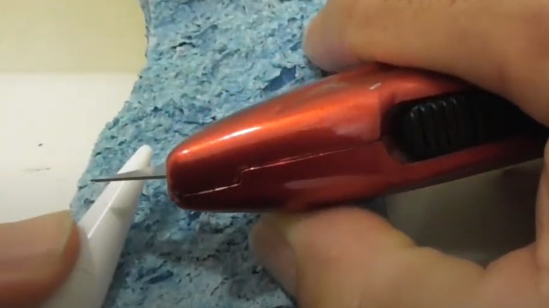 person cutting tube caulk with knife