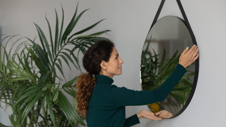 Woman hanging up mirror on wall