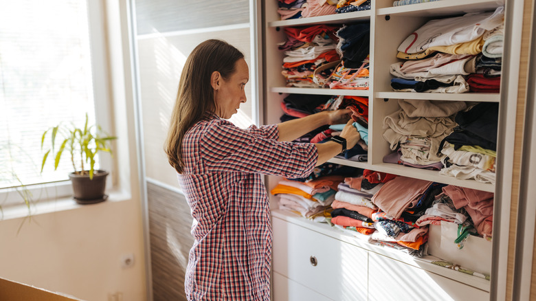 Woman organizing cluttered closet