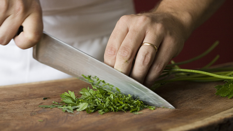 Person cutting cilantro, cutting board