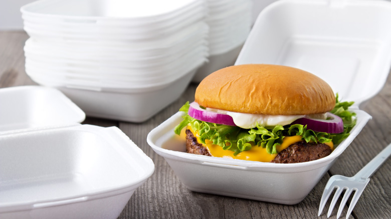 styrofoam containers with one holding a burger