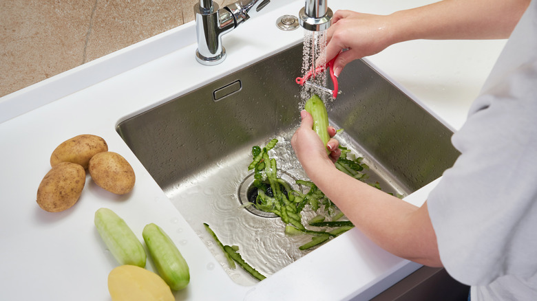 Someone putting food in kitchen sink drain