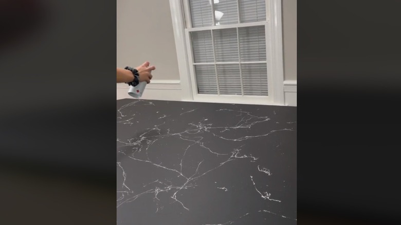 Person spraying marble paint on countertop