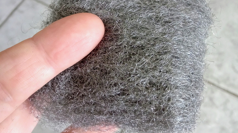 Man holds steel wool scrubber