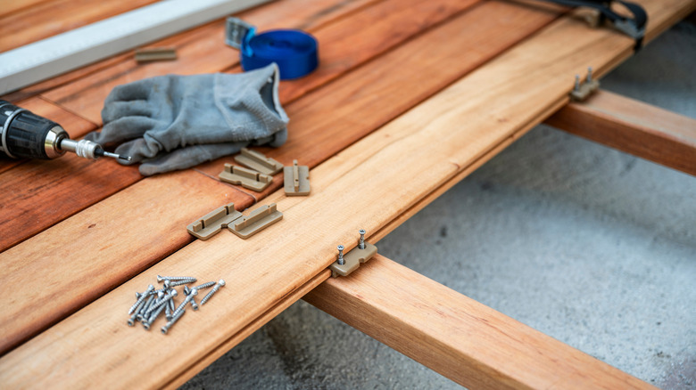 nails, drill, and work glove sit on top of wood planks