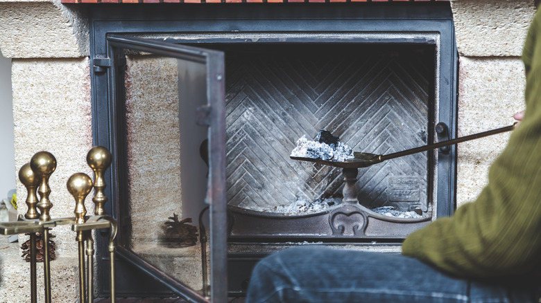 Person scooping ashes from fireplace 