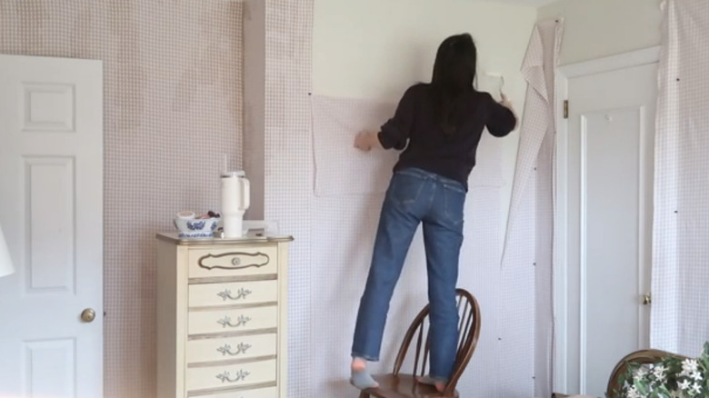 Woman applying fabric wallpaper