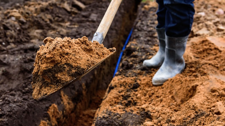 Person buries hose in trench