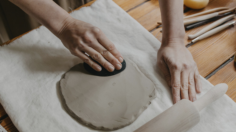 woman rolling clay with rolling pin