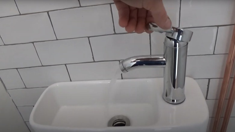 person operating faucet on toilet sink combo