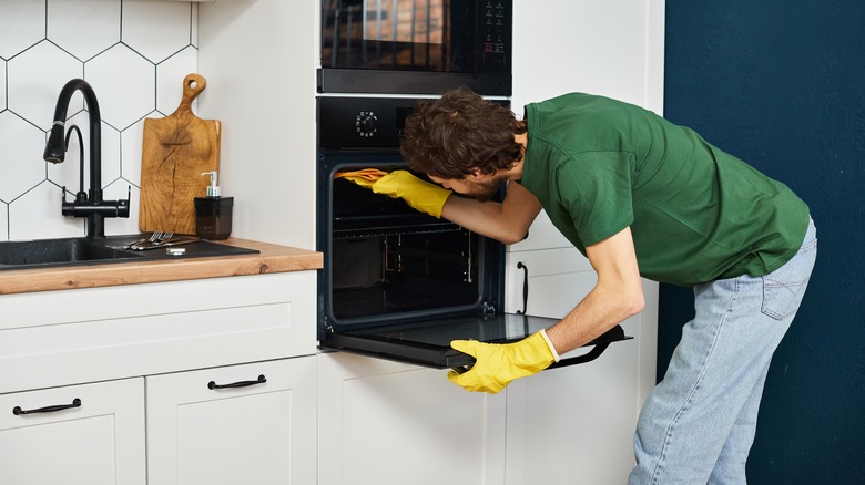 person cleaning oven