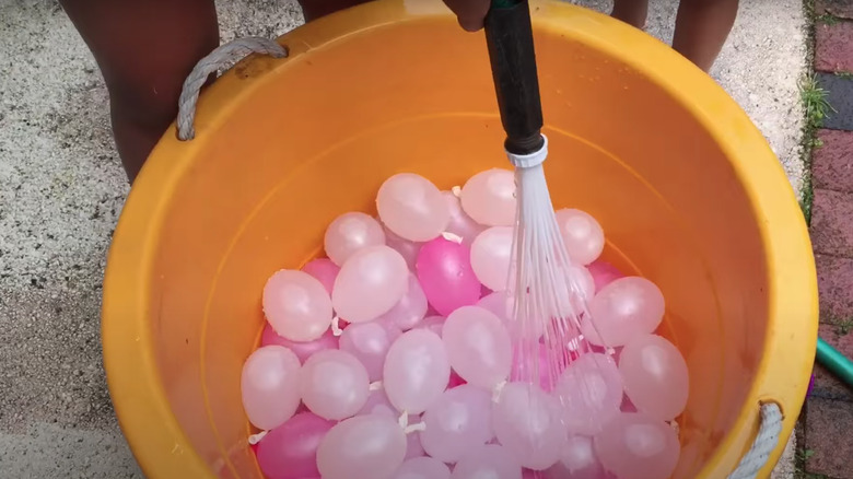 hose held over water balloons 