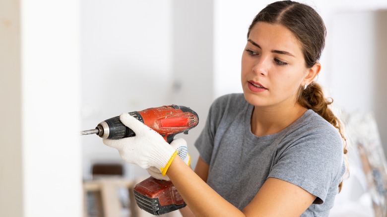 person drilling screw in wall