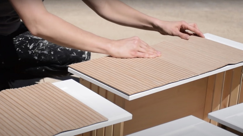 Woman gluing wooden fluted panels