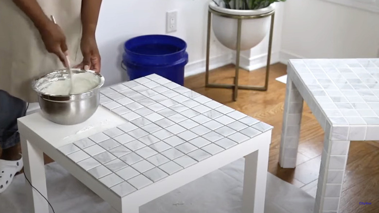 woman gluing white tiles to table