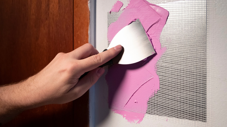 Person fixing hole in wall