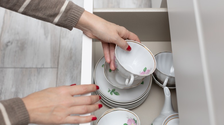 Person pulling teacup from drawer