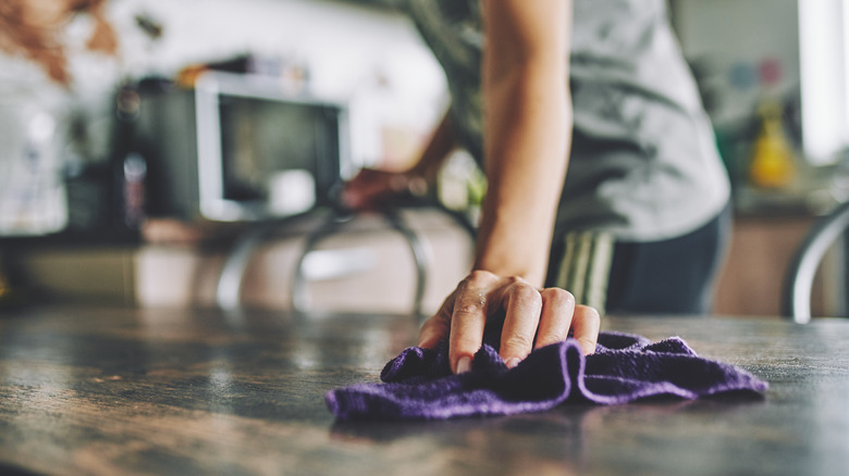 person cleaning countertop with rag