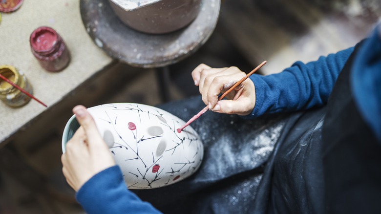 Person painting their ceramic vase