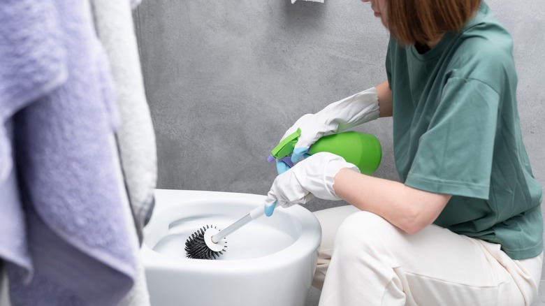 Woman wearing gloves cleaning toilet
