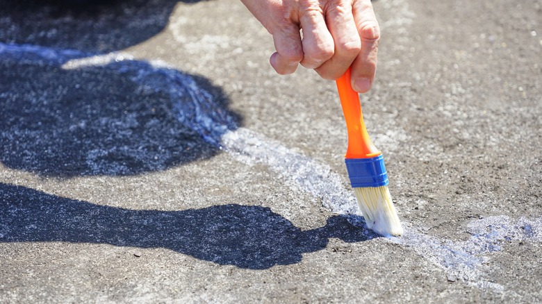 Person brushing glue on concrete 