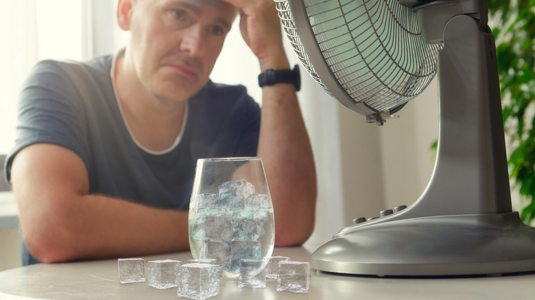 Man sweating with fan and ice cubes