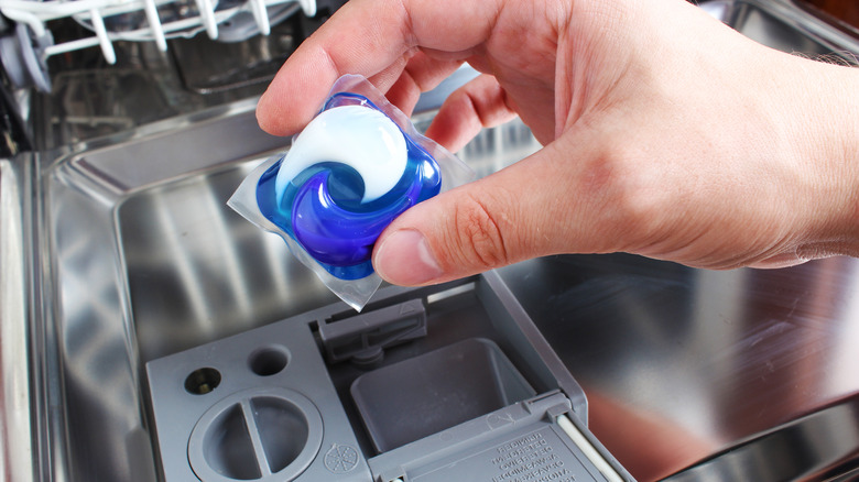 Person placing pod in dishwasher