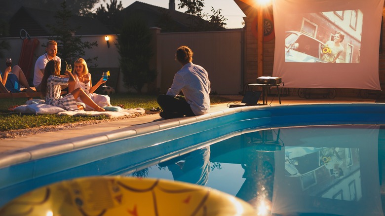 people relaxing beside pool watching a film