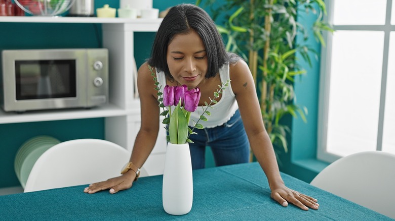 woman smelling flowers in vase