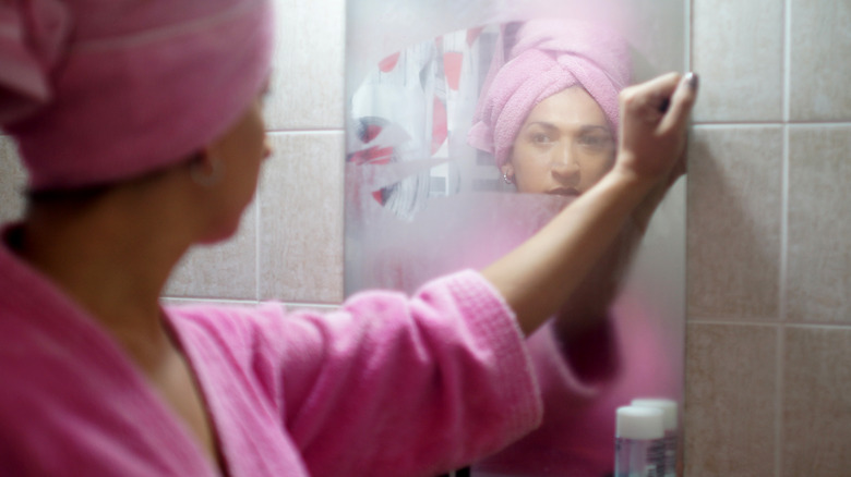 woman wiping steamy mirror