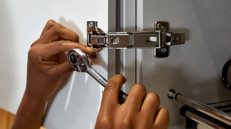 Person working on cabinet hinges