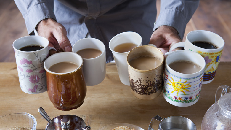 Person holding multiple mugs