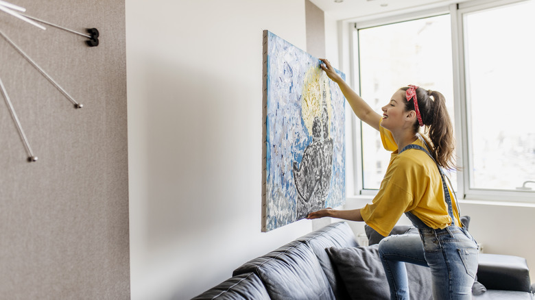 woman hanging painting on wall