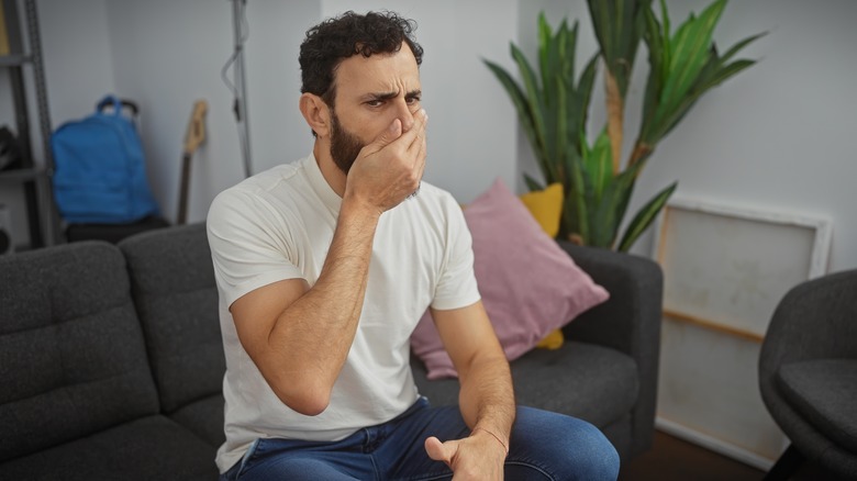 Man smelling unpleasant scent 