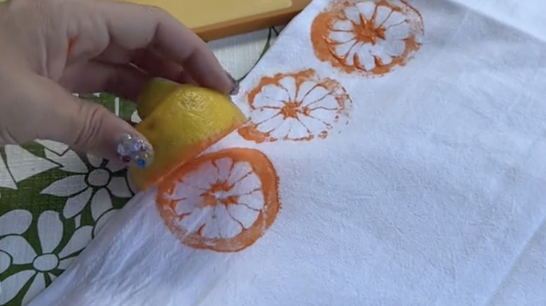 Person stamping tea towel with fruit