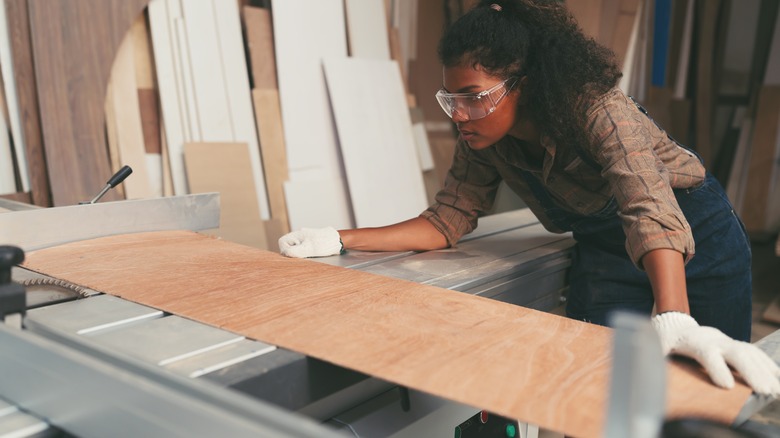 Woman sawing plywood