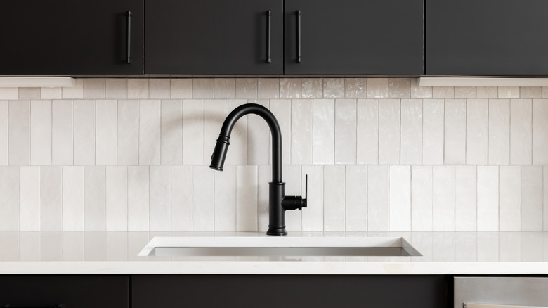 A white subway tile backsplash and black cabinets