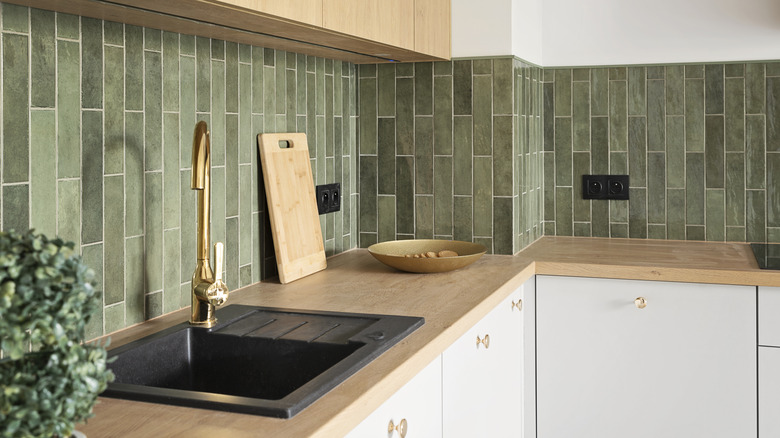 Green tiles are used in a backsplash in a kitchen.