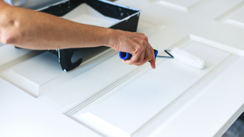 A person paints with a roller brush.