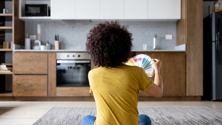 A person weighing paint color choices for the kitchen.