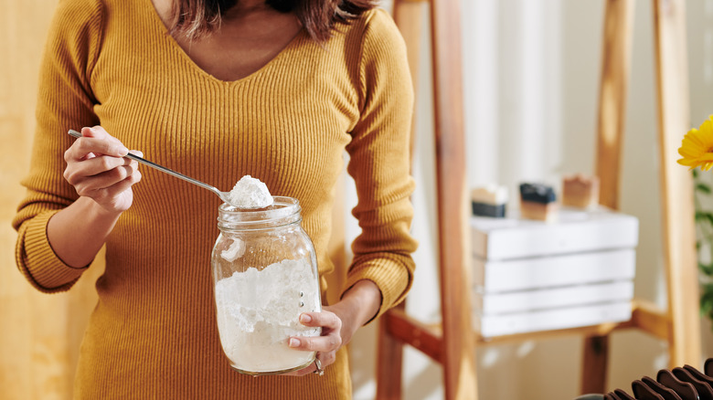 Woman scooping white powder from jar